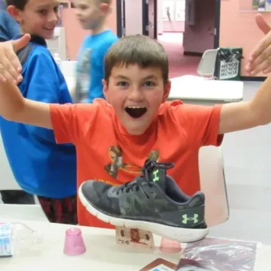 Excited student reacting during a magic trick involving a shoe balanced on cups