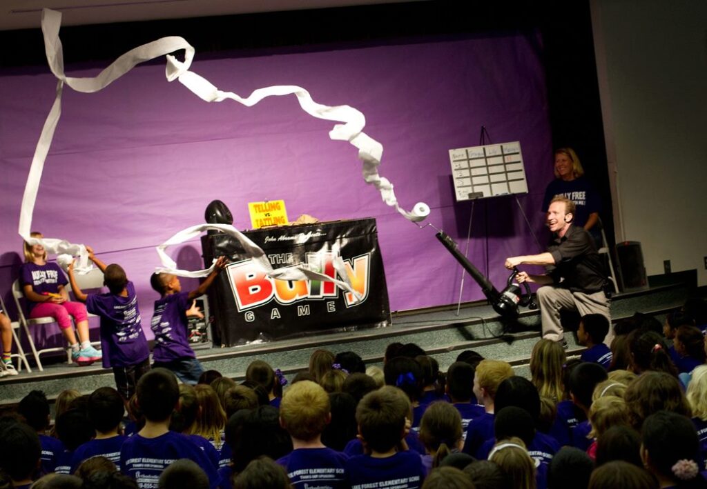 "Performer launches toilet paper stream over excited students during The Bully Game school assembly."